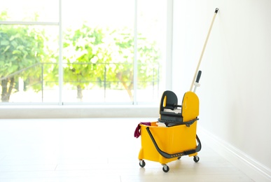 Photo of Mop bucket with cleaning supplies, indoors