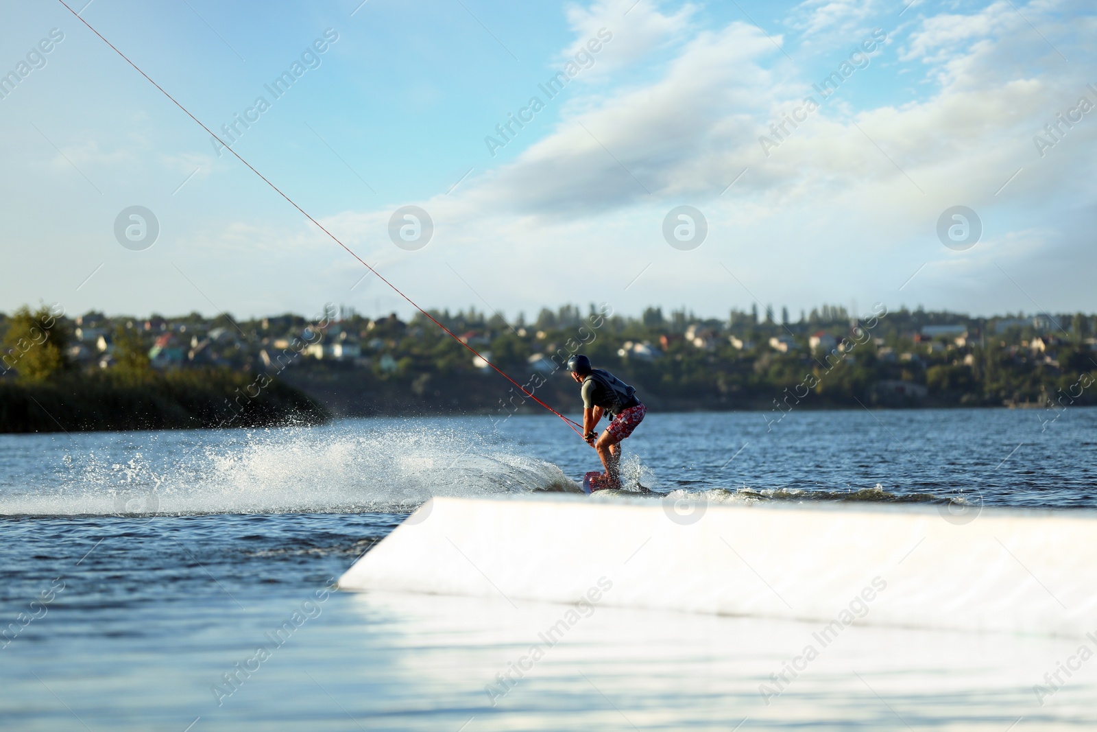 Photo of Teenage boy wakeboarding on river. Extreme water sport