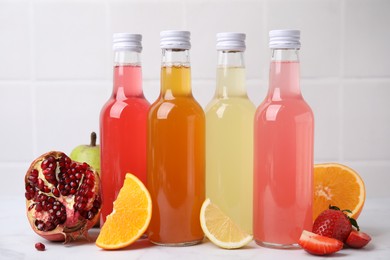 Delicious kombucha in glass bottles and fresh fruits on white table