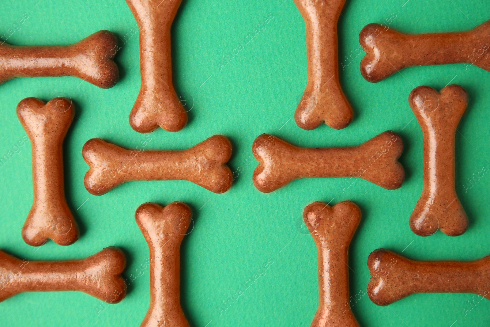 Photo of Bone shaped dog cookies on green background, flat lay