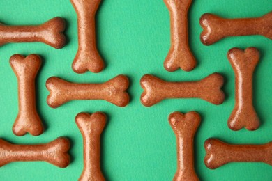 Bone shaped dog cookies on green background, flat lay