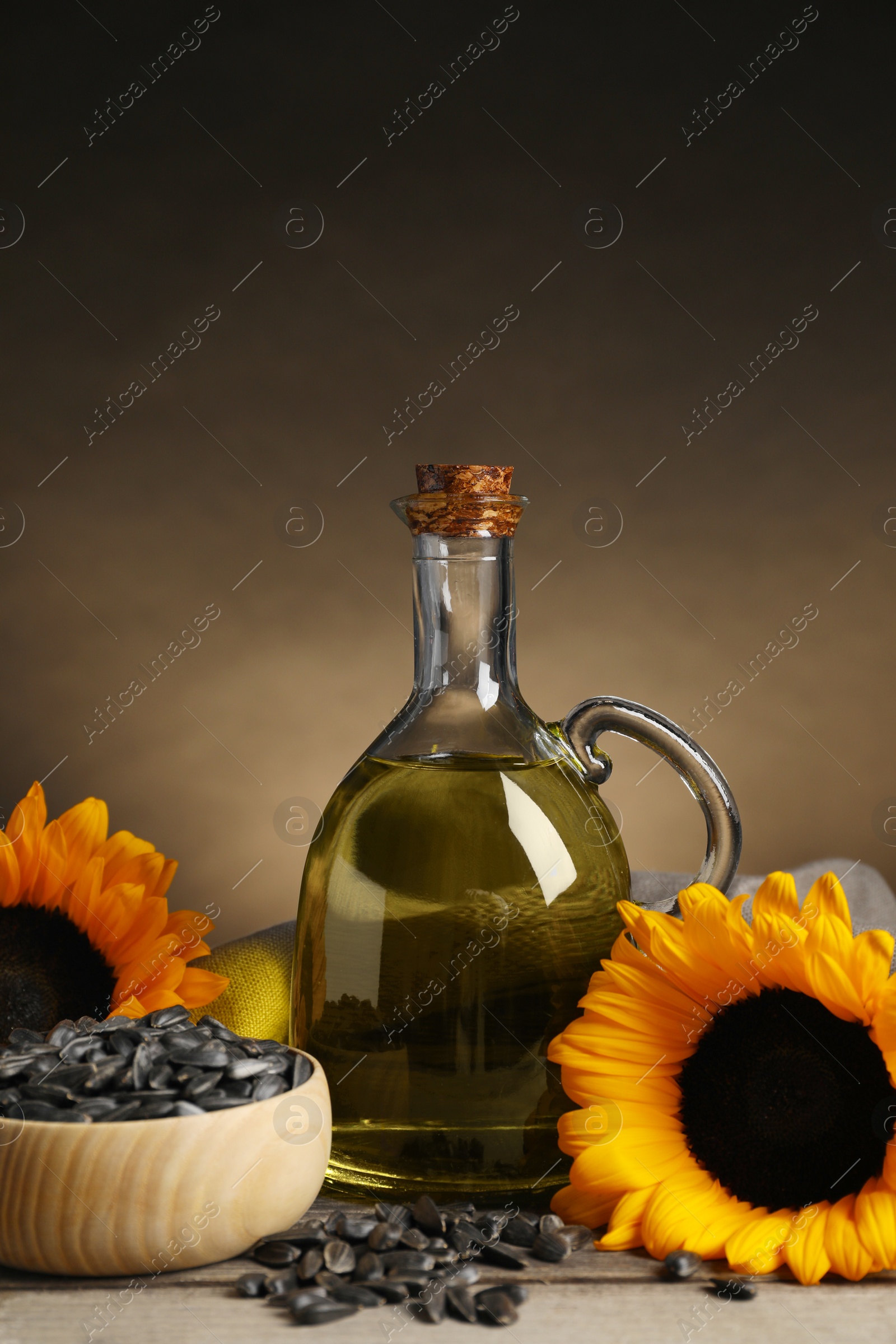 Photo of Sunflower cooking oil, seeds and yellow flowers on light grey table