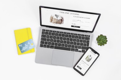 Online store website on laptop screen. Computer, smartphone, notebook, credit card and houseplant on white background, flat lay
