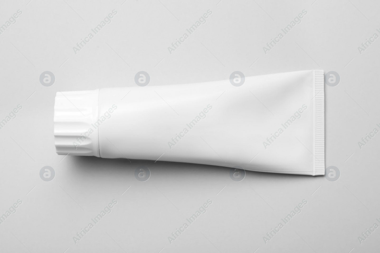 Photo of Blank tube of toothpaste on white background, top view