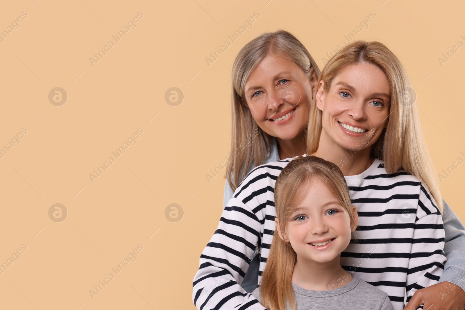 Photo of Three generations. Happy grandmother, her daughter and granddaughter on beige background, space for text