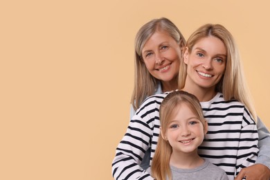 Photo of Three generations. Happy grandmother, her daughter and granddaughter on beige background, space for text