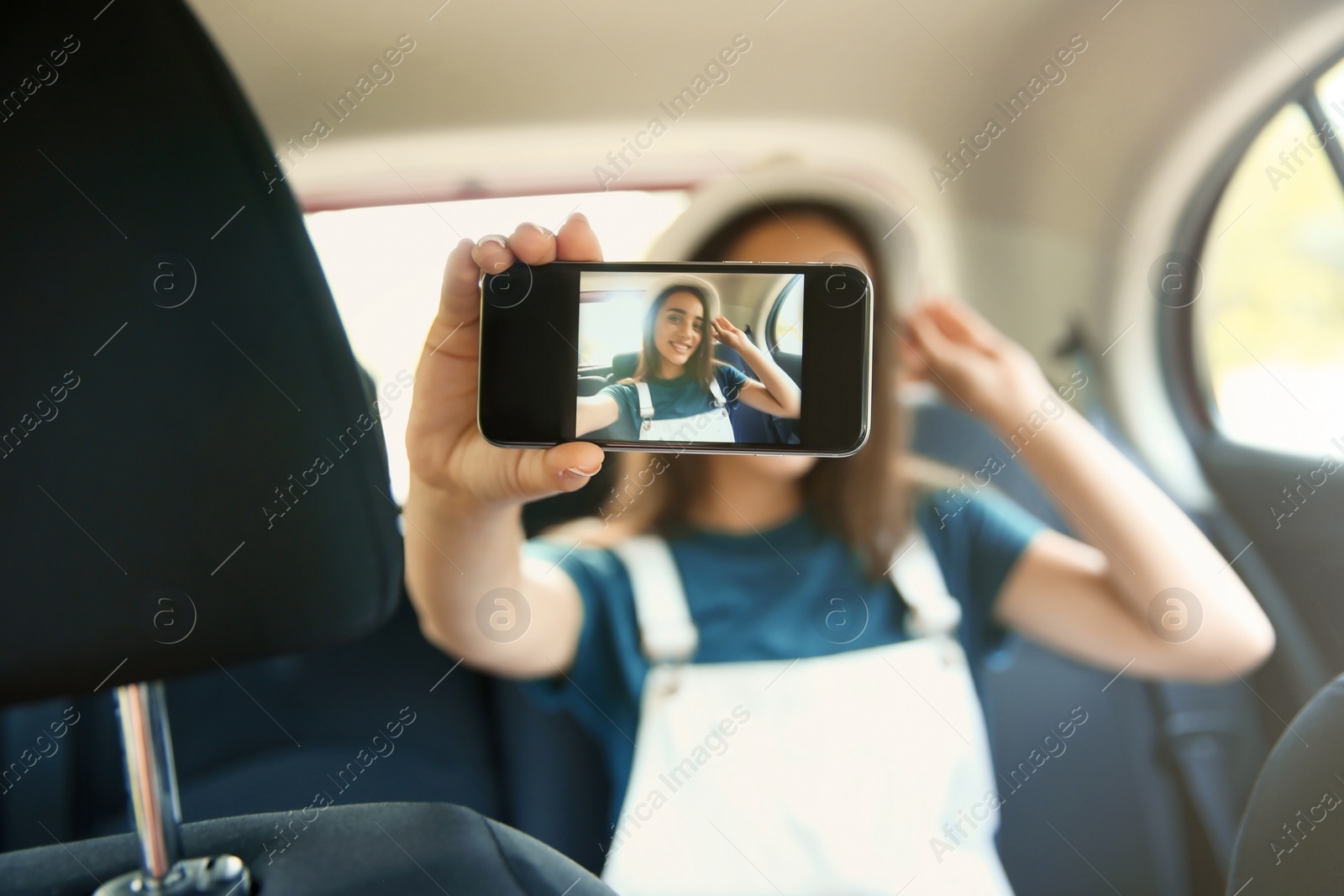 Photo of Happy young woman taking selfie in car