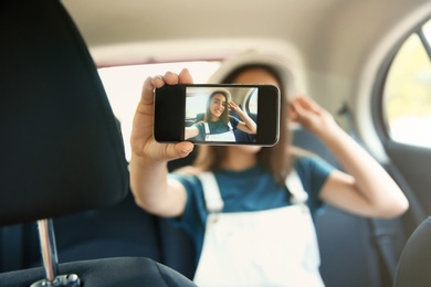 Happy young woman taking selfie in car