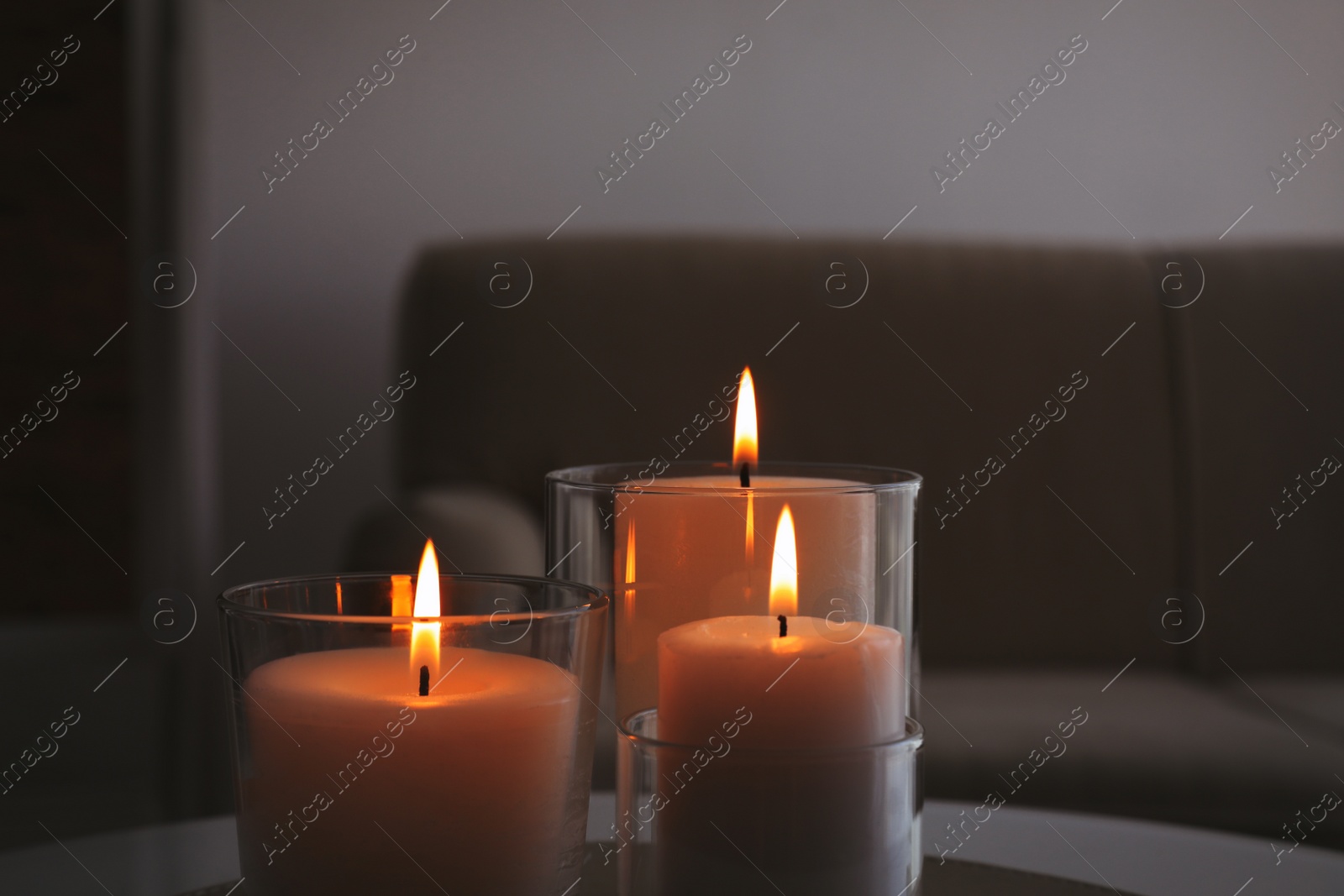 Photo of Burning candles in glass holders indoors, closeup
