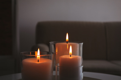 Photo of Burning candles in glass holders indoors, closeup