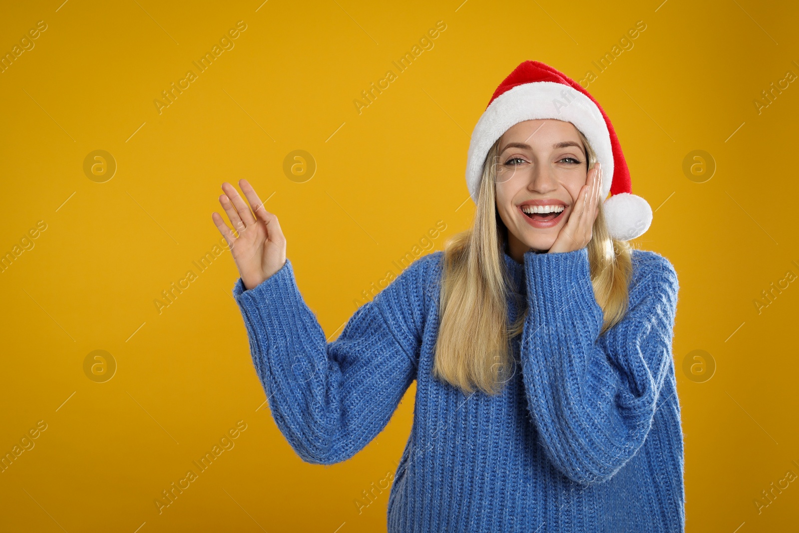 Photo of Happy woman in Santa hat on yellow background, space for text. Christmas countdown