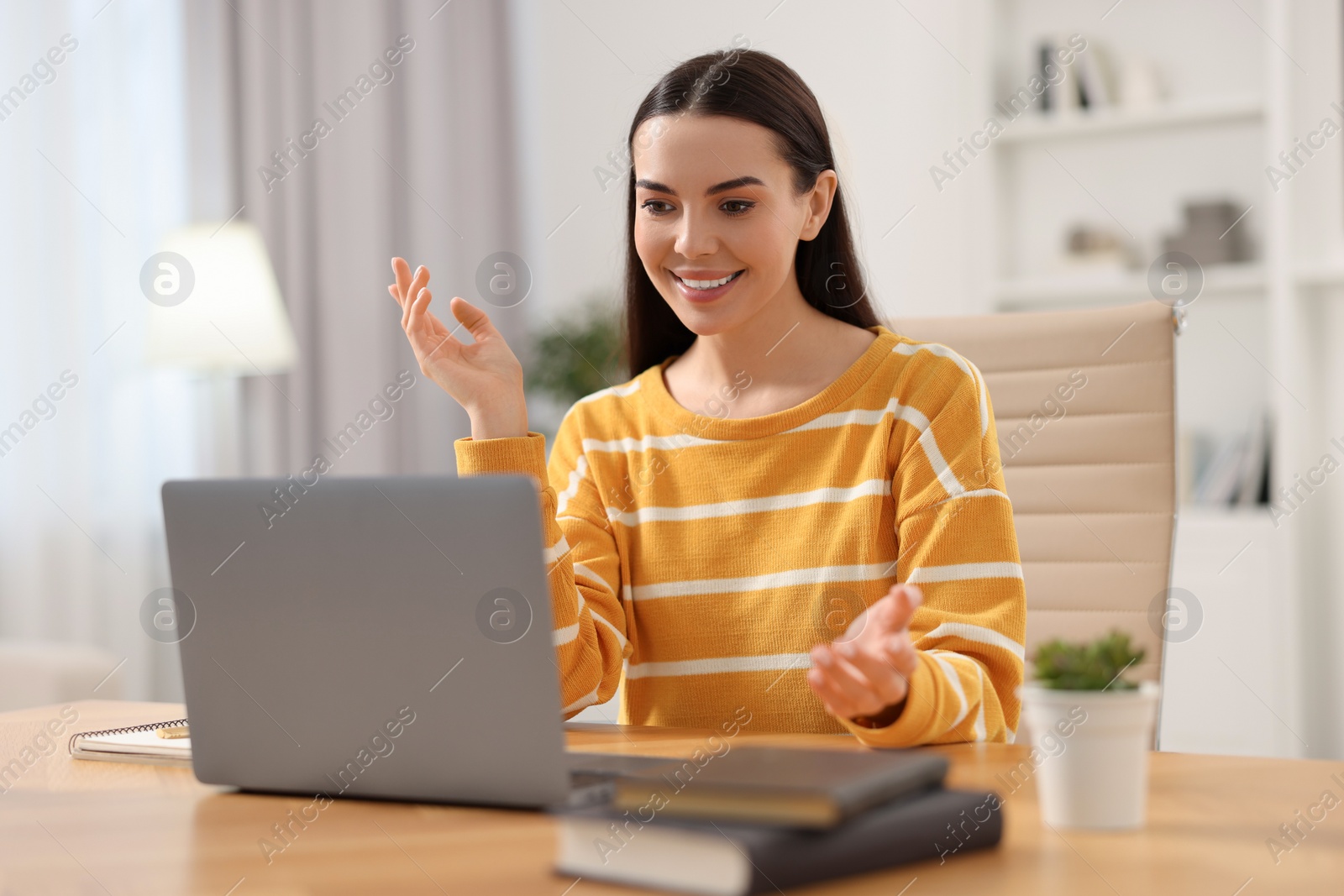 Photo of Young woman using video chat during webinar at table in room