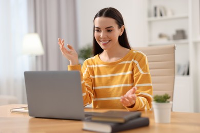 Young woman using video chat during webinar at table in room