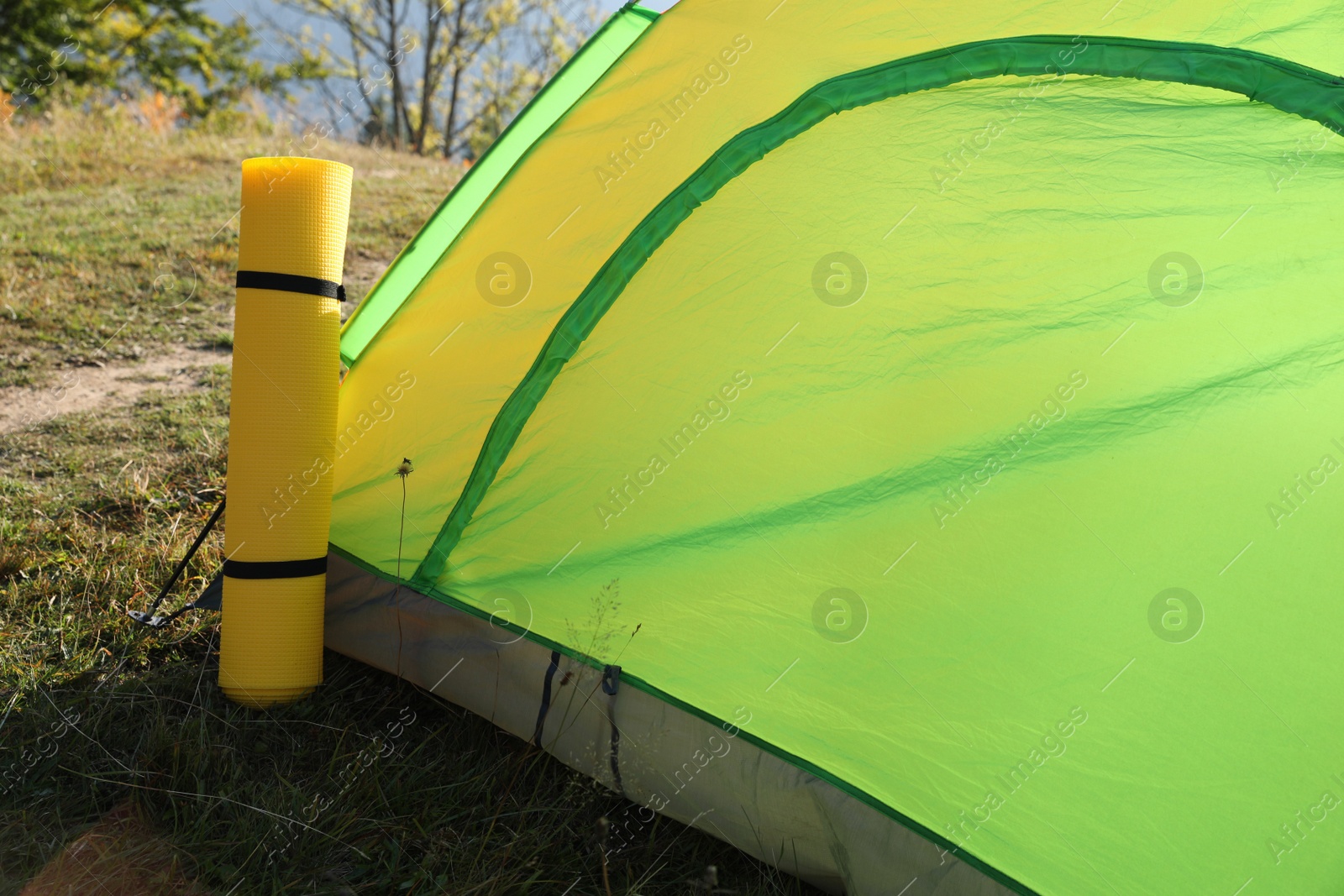 Photo of Sleeping mat near camping tent outdoors. Tourism equipment