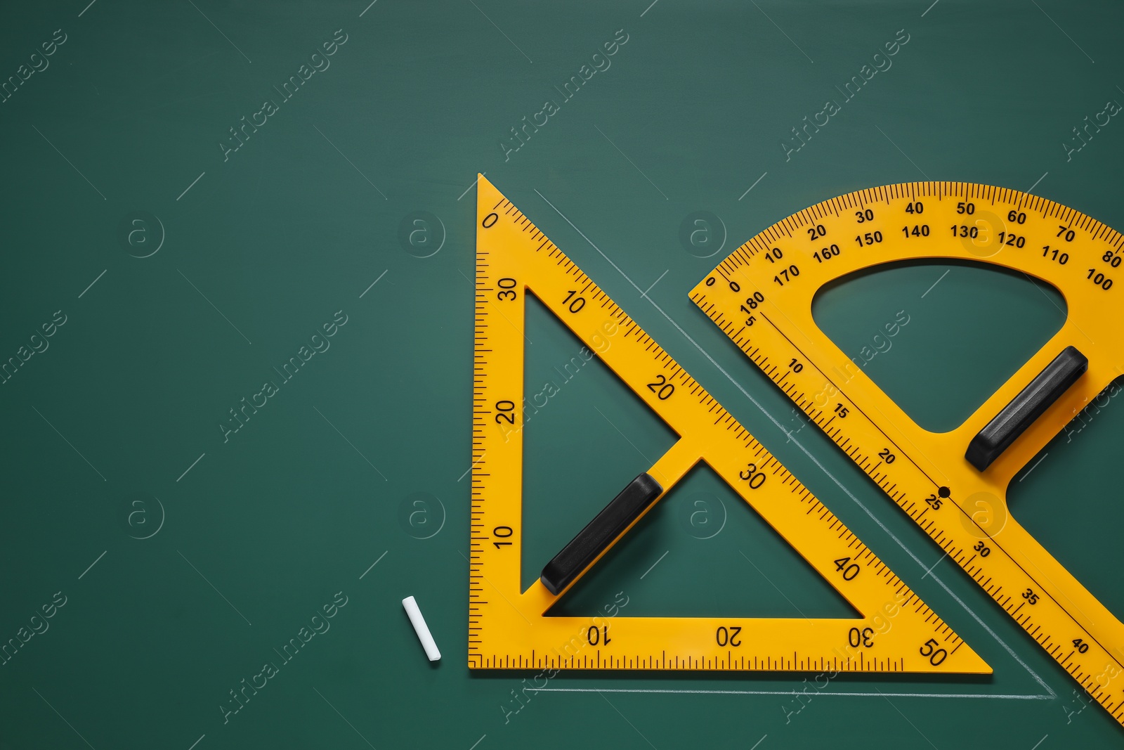 Photo of Protractor, triangle and chalk on green chalkboard, flat lay. Space for text