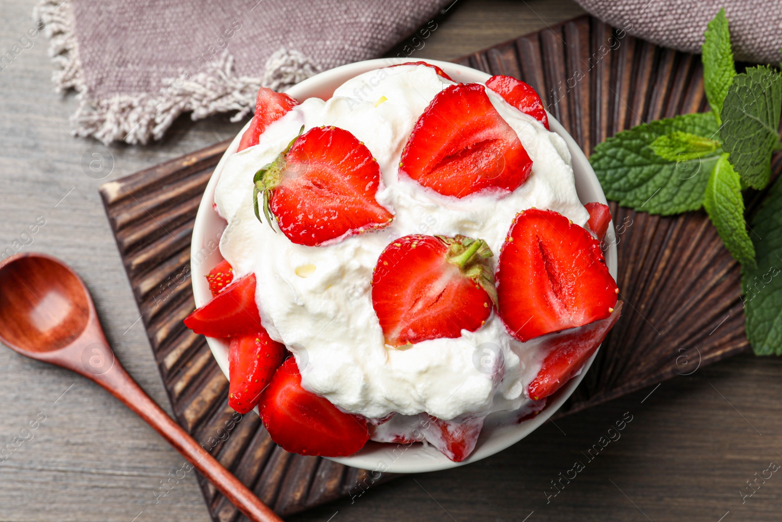 Photo of Delicious strawberries with whipped cream served on wooden table, flat lay