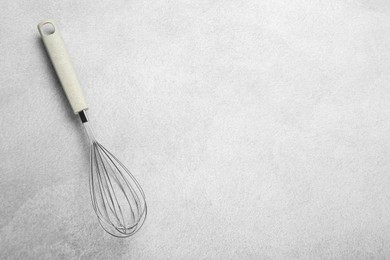 Photo of Metal whisk on gray table, top view. Space for text