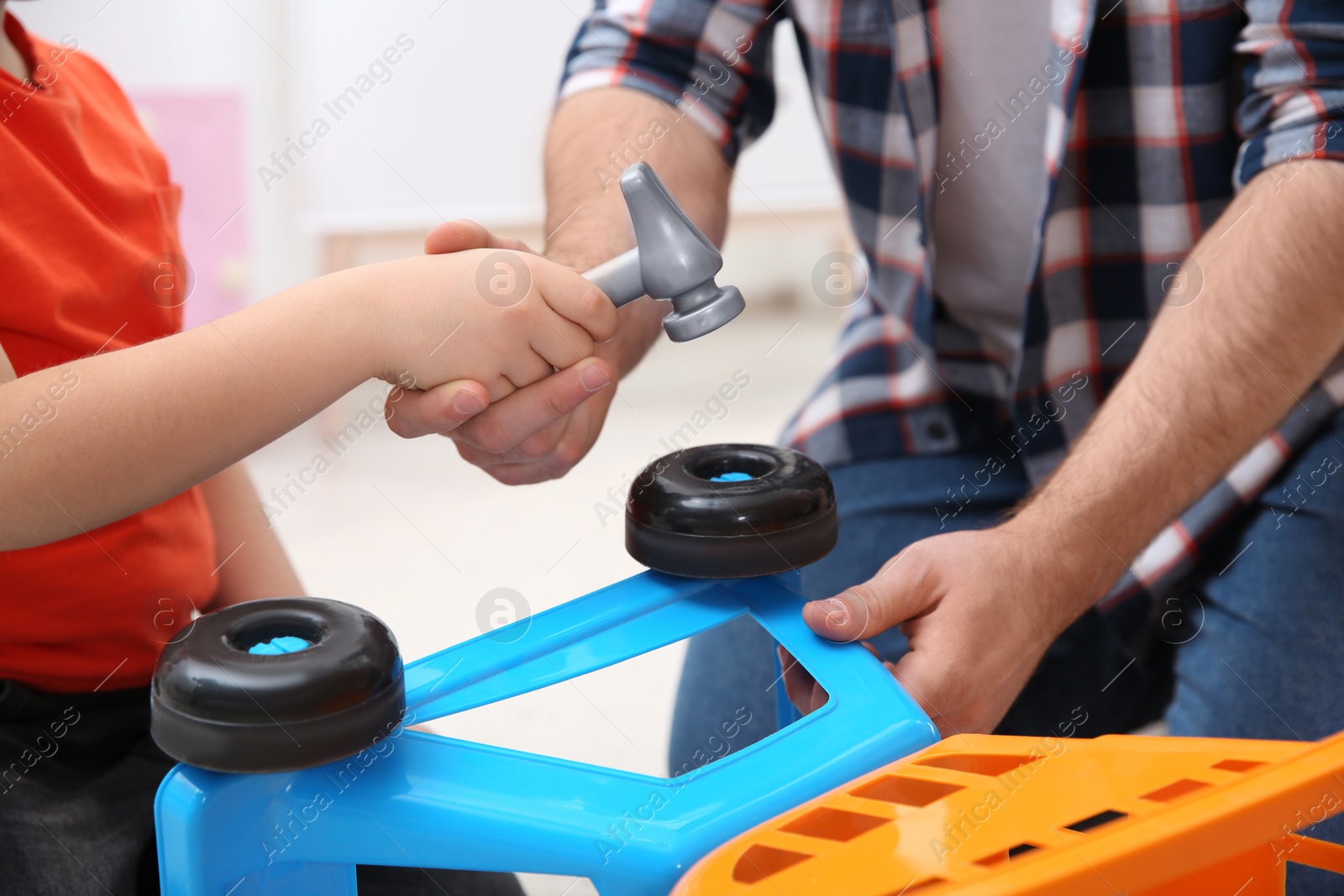 Photo of Man and his child as repairman playing with toy cart at home, closeup