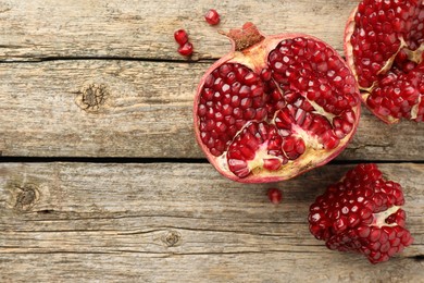 Photo of Cut fresh pomegranate on wooden table, top view. Space for text