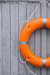 Orange life buoy hanging on light wooden wall
