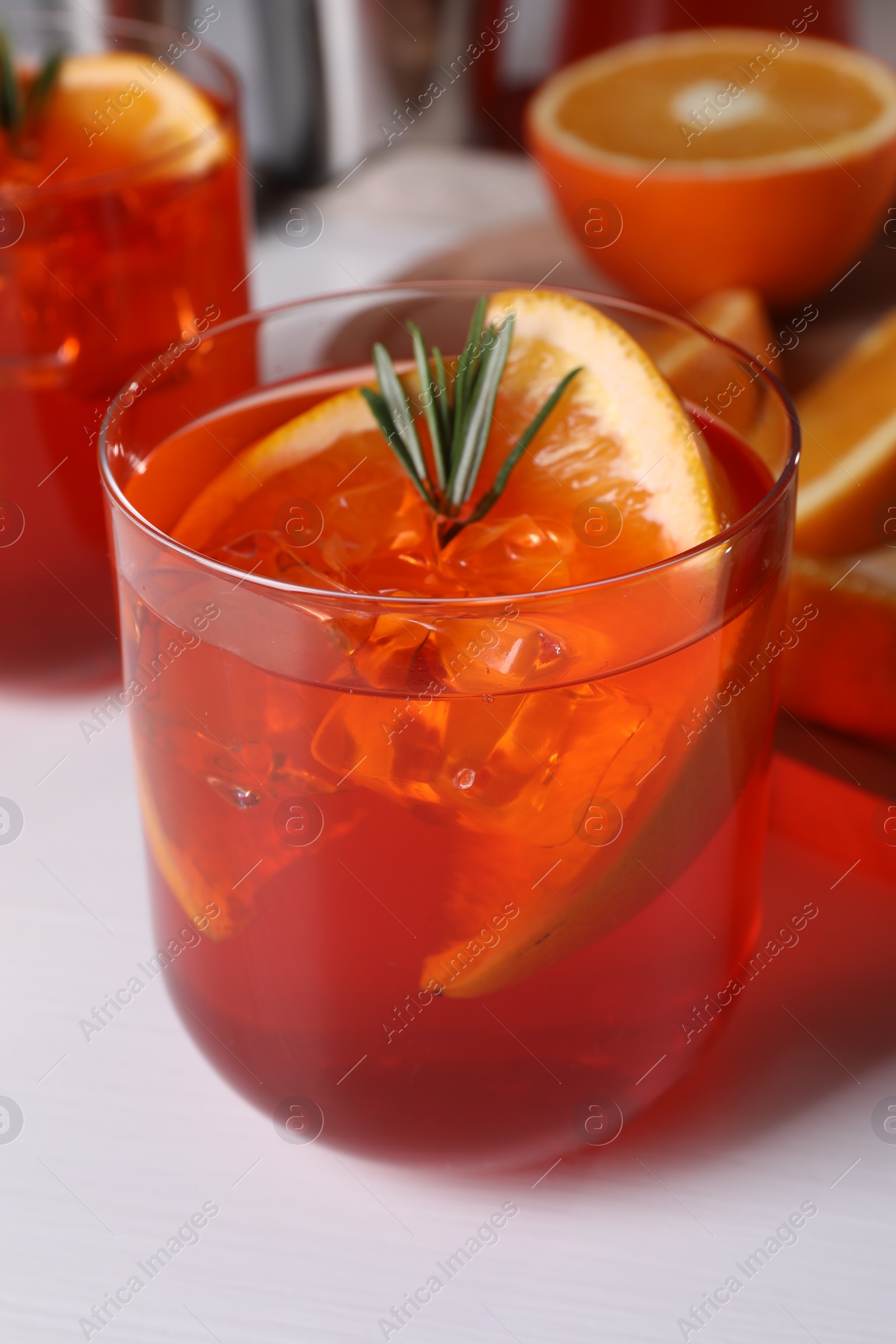 Photo of Aperol spritz cocktail, rosemary and orange slices on white wooden table, closeup