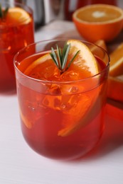 Photo of Aperol spritz cocktail, rosemary and orange slices on white wooden table, closeup