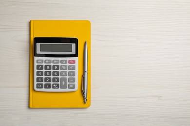 Calculator, notebook and pen on white wooden table, top view with space for text