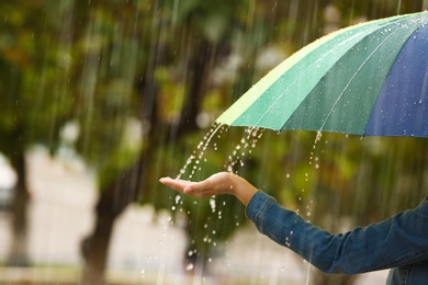 Photo of Woman with bright umbrella under rain on street, closeup