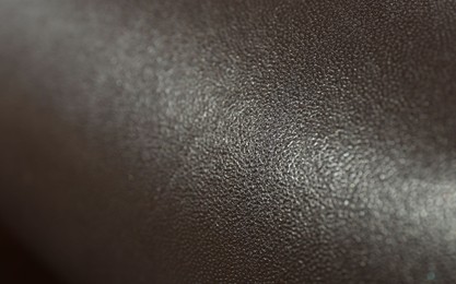 Dark brown natural leather as background, closeup view