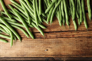 Photo of Fresh green beans on wooden table, flat lay. Space for text