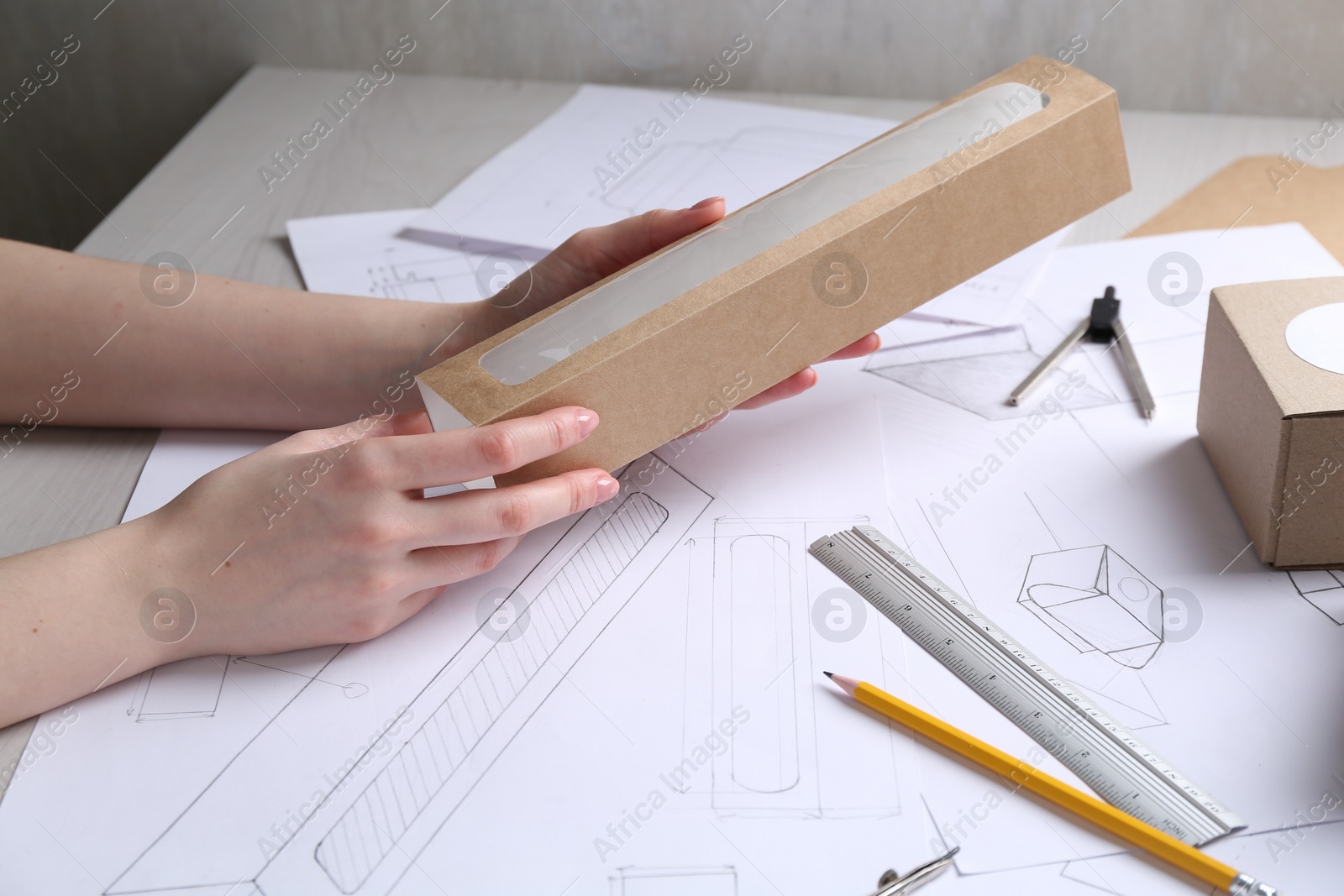 Photo of Woman creating packaging design at light wooden table, closeup