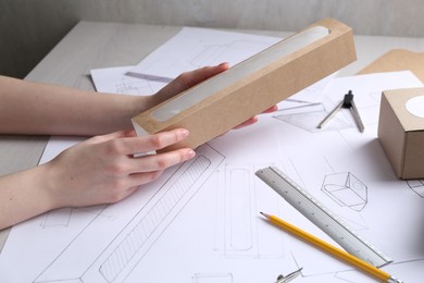 Photo of Woman creating packaging design at light wooden table, closeup