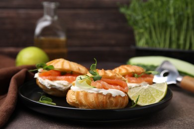 Delicious profiteroles with cream cheese, salmon and cucumber on textured table, closeup
