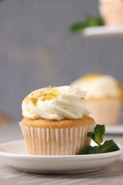 Photo of Delicious lemon cupcake with white cream and mint on table, closeup. Space for text
