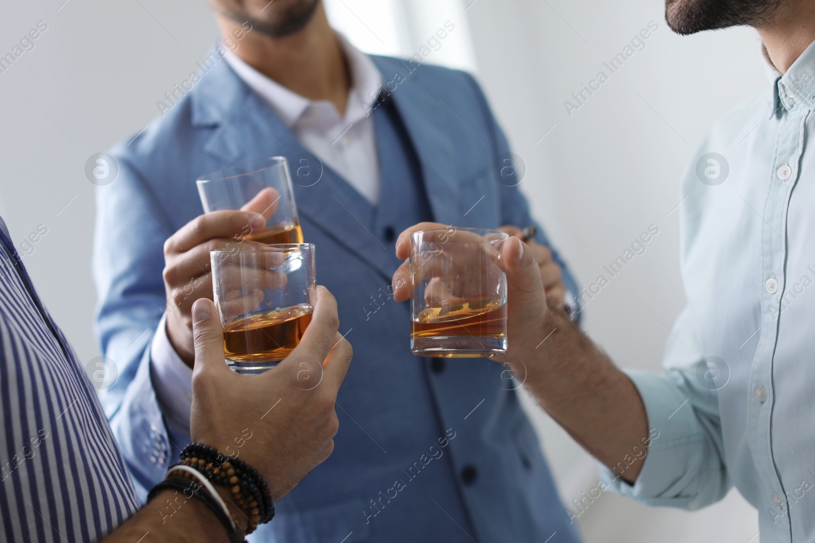 Photo of Group of friends drinking whiskey together indoors, closeup