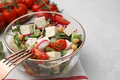 Photo of Bowl of tasty salad with tofu and vegetables on light grey table, closeup. Space for text