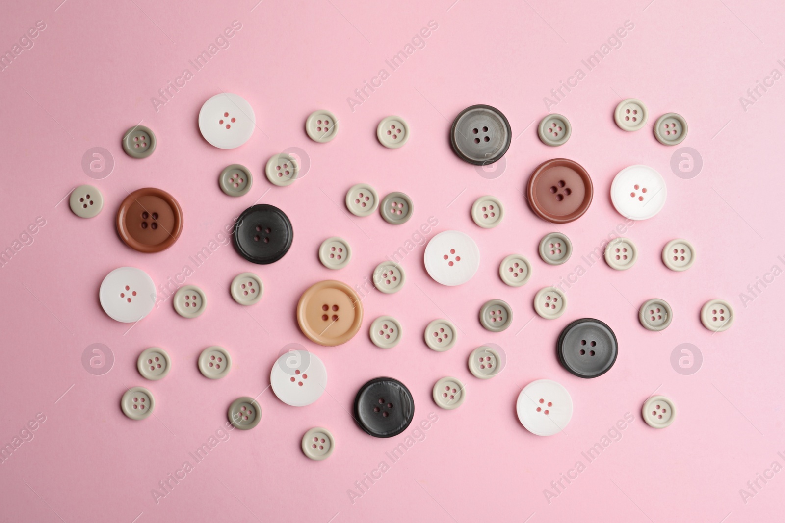 Photo of Many sewing buttons on pink background, flat lay