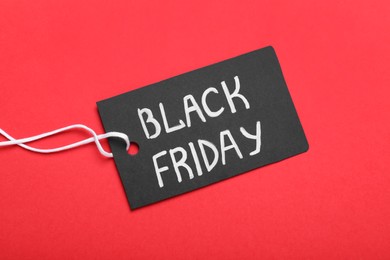 Photo of Tag with words Black Friday on red background, top view