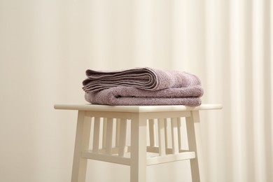 Violet towels on stool against white wall