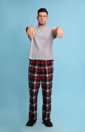 Photo of Somnambulist in pajamas on light blue background. Sleepwalking