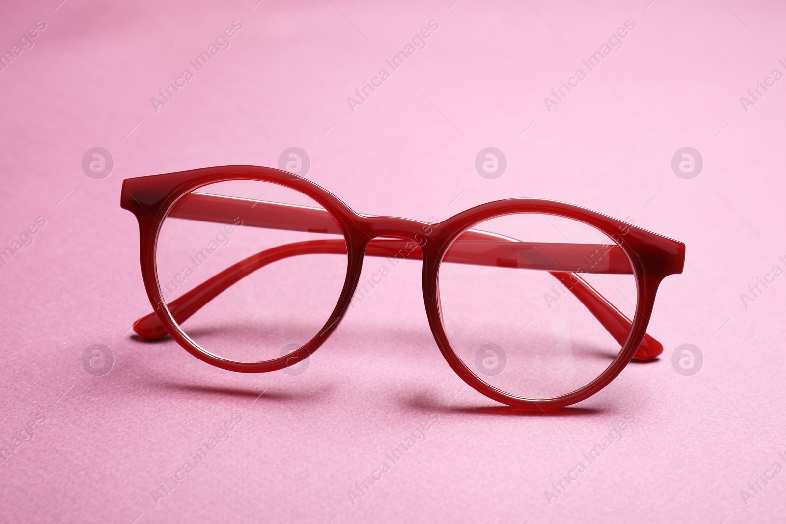 Photo of Stylish pair of glasses with red frame on pink background