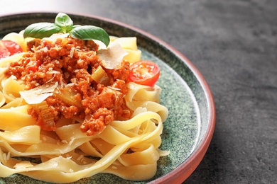 Photo of Plate with delicious pasta bolognese on grey background, closeup