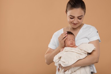 Mother with her cute newborn baby on beige background. Space for text