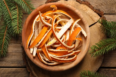 Photo of Dry orange peels and fir branches on wooden table, flat lay
