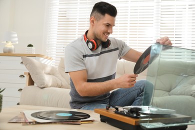 Happy man choosing vinyl record to play with turntable at home