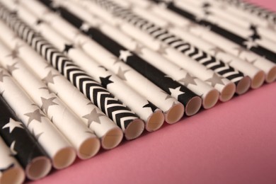 Many paper drinking straws on pink background, closeup