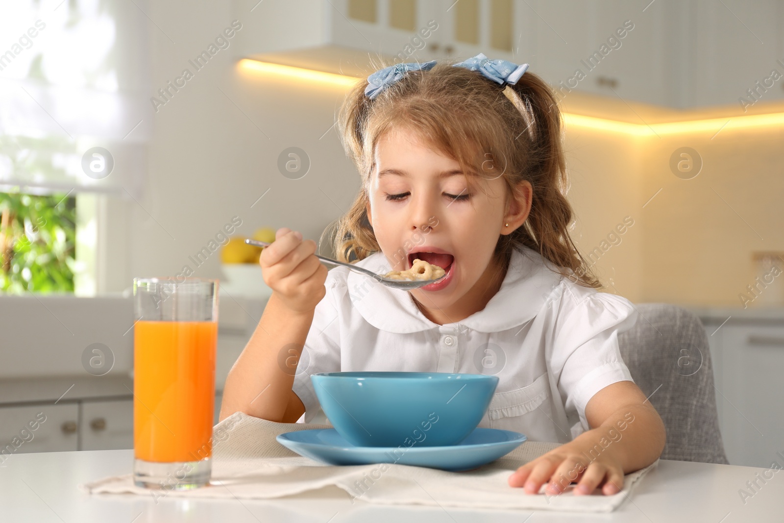 Photo of Little girl having breakfast in kitchen. Getting ready for school