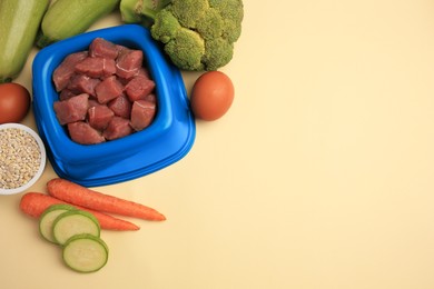 Photo of Raw meat in bowl and healthy products for pet on beige background, above view. Space for text