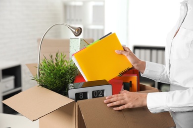 Young woman packing stuff in box at office, closeup