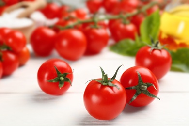 Fresh ripe cherry tomatoes on white wooden table, closeup